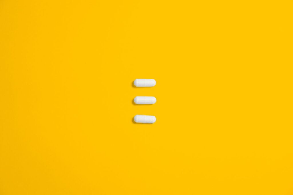 White pills arranged on a vibrant yellow background, emphasizing simplicity and healthcare.